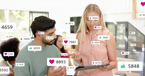 Team collaborating with tablet showing social media likes, follower counts, analytics