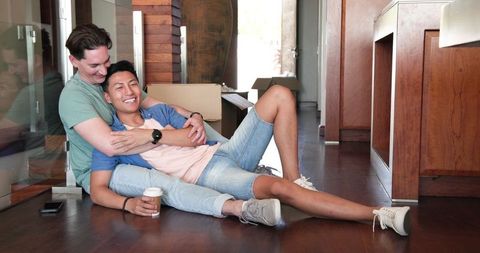 Couple Sitting on Floor Laughing and Relaxing with Coffee