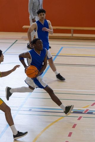 Diverse Male Basketball Players Engaged in Intense Gymnasium Match