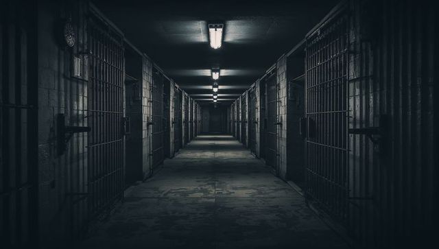 Eerie Prison Corridor with Dim Lighting and Metal Barred Doors