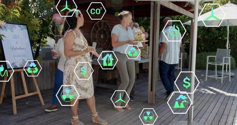 Group celebrating 60th birthday on backyard deck carrying cake with sustainability icons