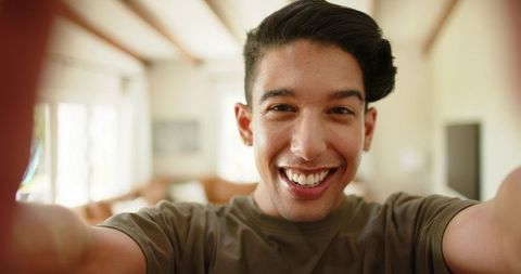 African american man late 20s taking smiling selfie in cozy living room with natural light