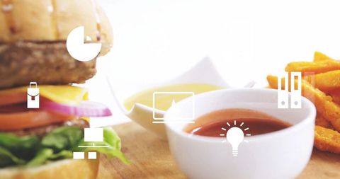 Gourmet cheeseburger with fries and sauce featuring digital interface icons