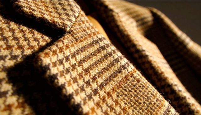 Macro close-up vintage tweed jacket lapel showcasing houndstooth wool texture and stitching