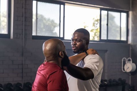African american athletes sparring and practicing shoulder control drill in industrial gym