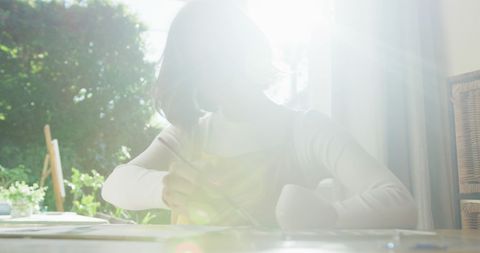 Woman painting in sunlit room at home