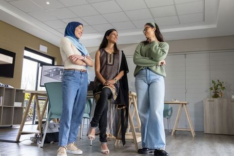 Collaborating diverse female design team brainstorming in modern studio wearing hijab and kurta