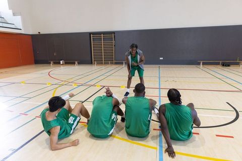 Coach leading basketball players through court drill in indoor gymnasium