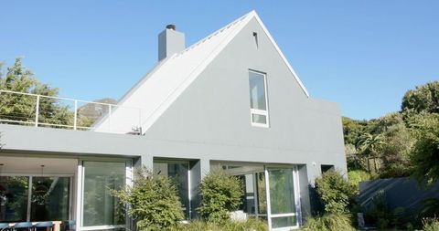 Contemporary grey home with steep white gable roof, large glass windows and garden terrace