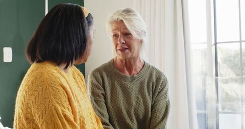 Female friends sharing candid moment by bright window