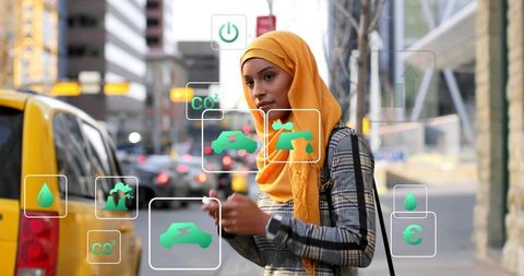 Woman wearing mustard hijab using smartphone with ar eco and transit icons in city