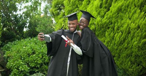 Graduates celebrating with selfie during outdoor ceremony