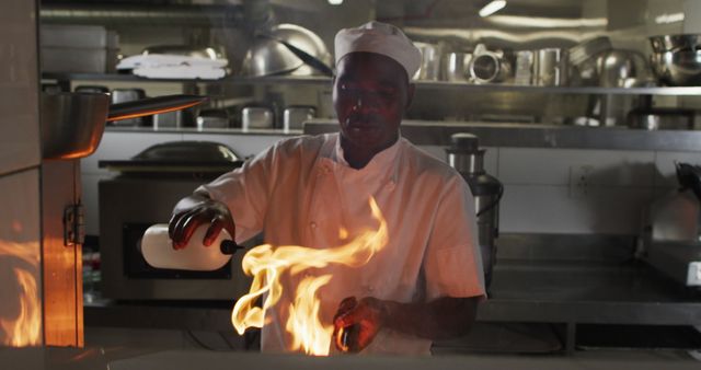 African american male chef frying in pan in restaurant kitchen. Working in a busy restaurant kitchen.