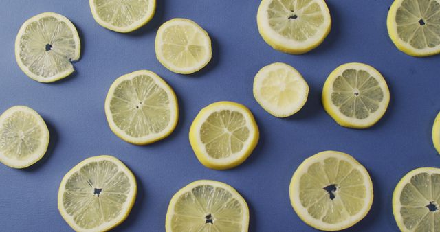 Bright and vibrant lemon slices arranged on blue background. Perfect for use in food blogs, beverage advertisements, nutrition articles, or culinary websites promoting healthy eating and fresh ingredients.