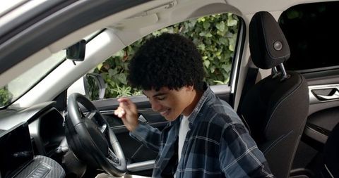 Young man adjusting rearview mirror inside car for safe drive