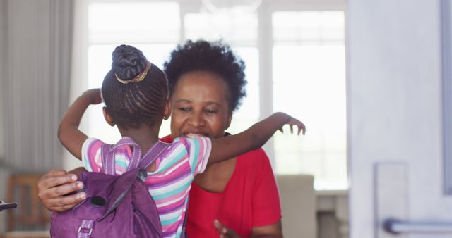 Image of african american granddaughter with schoolbag coming home and hugging happy grandmother. Childhood, family and domestic life.
