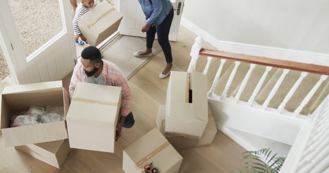 Happy african american family moving house and holding cartons. Domestic life, lifestyle, family and change, unaltered.