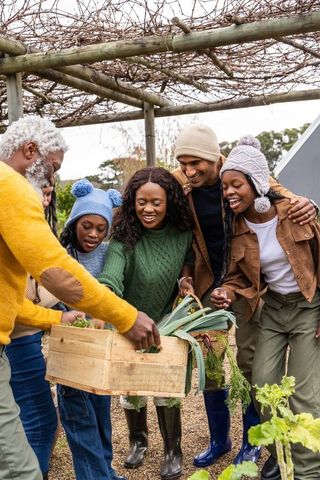 African american family harvesting leeks in backyard garden under pergola