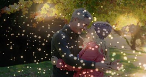Couple embracing in sunlit autumn park with golden foliage and romantic bokeh lights