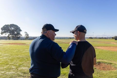 Coach guiding baseball player with supportive hand on shoulder during practice