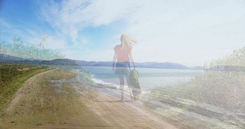 Woman walking sunlit coastal boardwalk pulling suitcase double exposure solitude