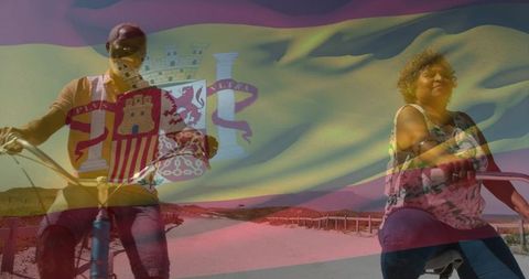 Couple cycling along spanish coast with flag overlay on sunlit dunes for tourism
