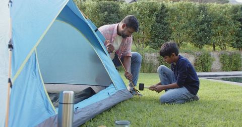 Father and son bonding over tent setup in backyard