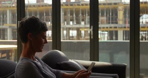 Woman with Grey Hair Checking Smartphone in Urban Office Setting