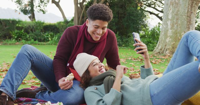 Image of biracial couple warmly spending time in the garden and using smartphone. Domestic lifestyle and leisure time in the garden.