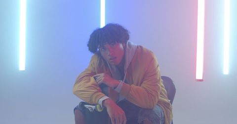 Youthful man holding skateboard with led lighting atmosphere