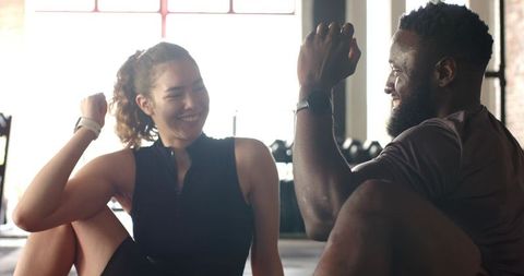 Diverse friends celebrating workout with high-five in gym