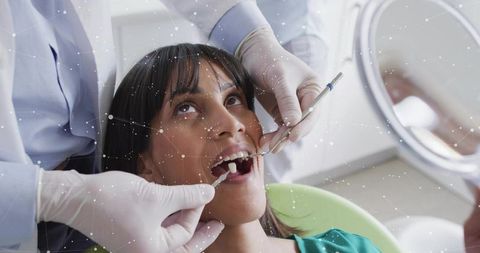 Dentist examining female patient during routine dental checkup with mirror and probe