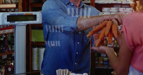Vendor handing fresh carrots to customer at market checkout with scale and denim shirt