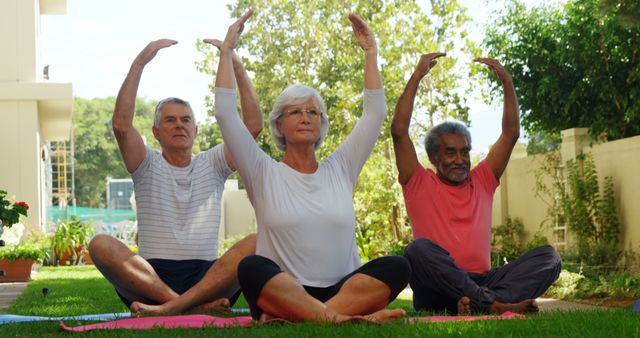 Senior adults practicing yoga together outdoors, focusing on flexibility and relaxation. This image can be used for promoting healthy living, senior fitness programs, group activities, wellness workshops, meditation retreats, and community activities.