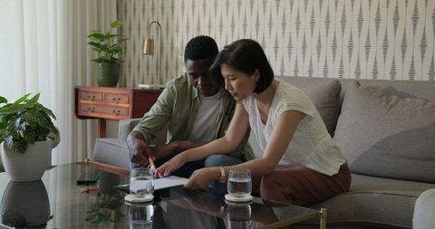 Interracial couple planning wedding details on sofa