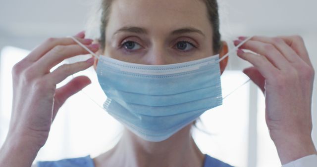 Healthcare Worker Adjusting Surgical Mask Indoors - Download Free Stock Images Pikwizard.com