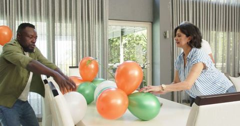 Diverse Group Setting Up Colorful Balloon Decorations Indoors