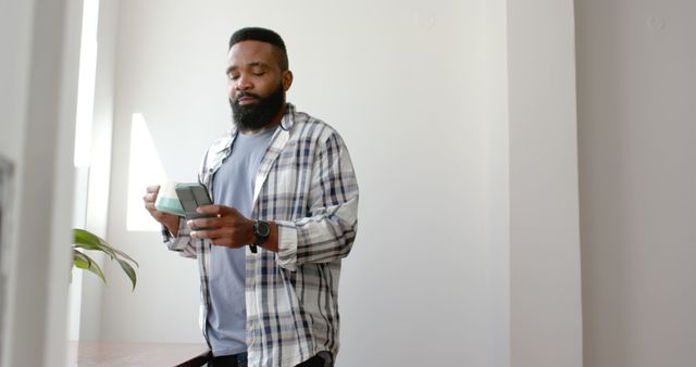 African American Man Holding Smartphone in Bright Room - Download Free Stock Images Pikwizard.com