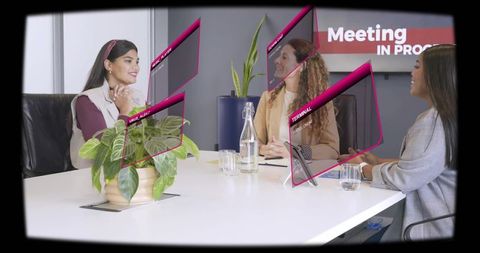 Women collaborating in augmented reality meeting with magenta ar overlays in boardroom
