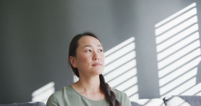 Thoughtful Woman Pondering Indoors Near Window with Striped Lighting - Download Free Stock Images Pikwizard.com