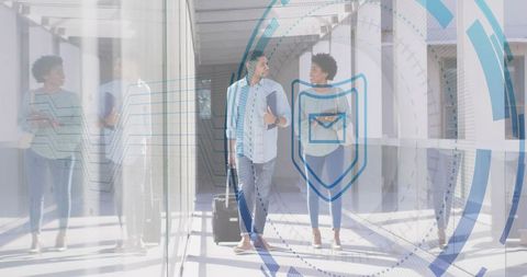 Business couple walking through secure glass terminal with security overlay and rolling suitcase