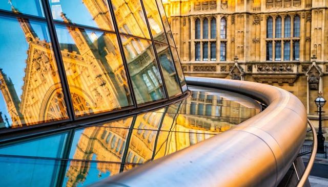 Curved glass reflecting gothic facade on contemporary terrace with sweeping steel railing