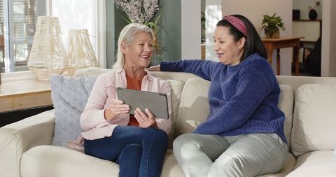Senior Women Conversing and Connecting with Tablet on Cozy Sofa