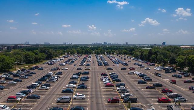 Aerial View of Commercial Parking Lot with Symmetrical Rows of Vehicles under Blue Sky