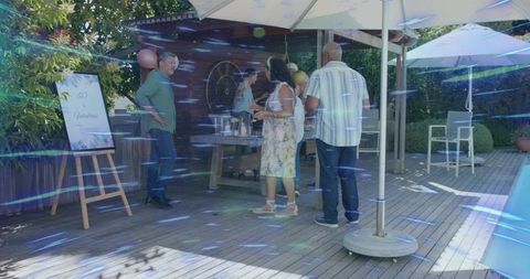 Friends chatting at backyard pool party on deck with pergola and balloons