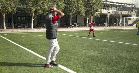 Soccer coach overseeing young players at practice on sunny day