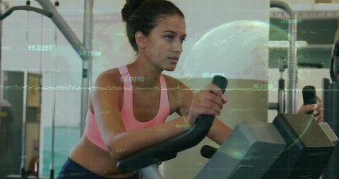 Focused Woman Exercising on Stationary Bike with Digital Data Overlay