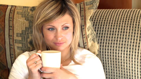 Smiling Woman Relaxing with Coffee on Comfortable Sofa