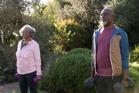 Senior Couple Exercising in Garden with Dumbbells, Embracing Wellness Lifestyle