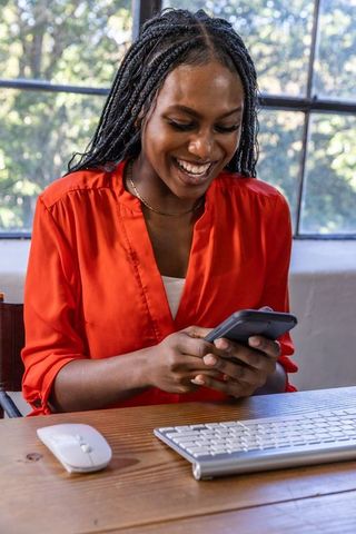 Smiling woman checking smartphone at modern workplace